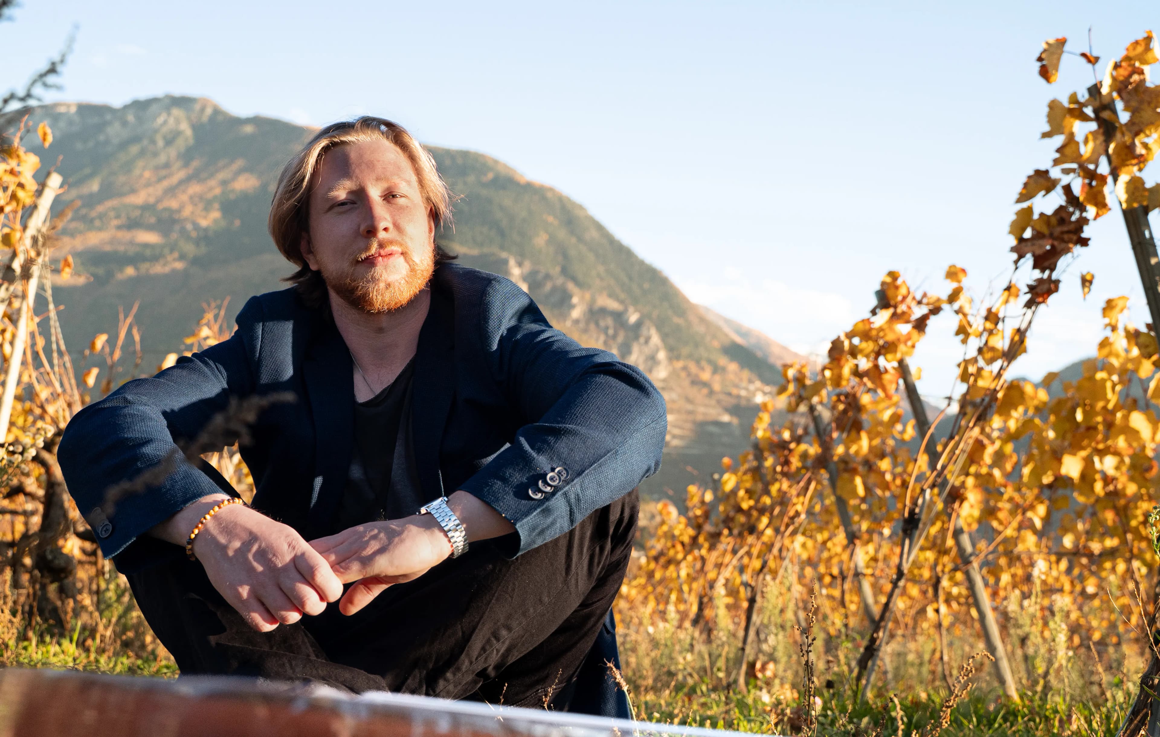 Jakub Bachleda seated in a vineyard with mountains in the background.